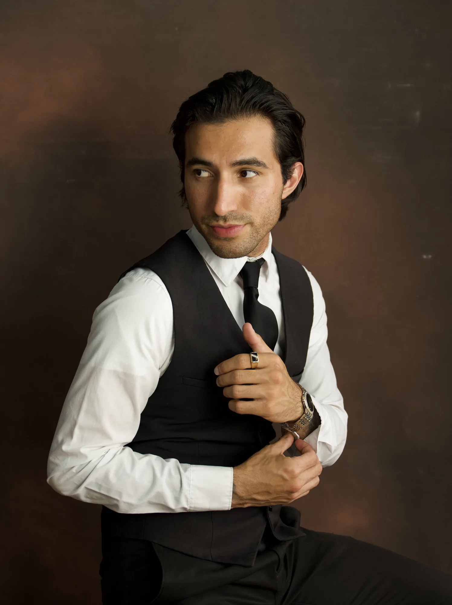 Man in a vest and tie adjusting his cuff