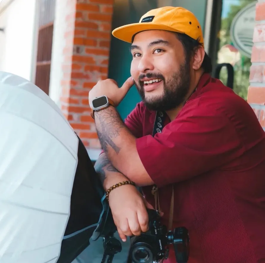 Man in an orange cap smiling at work with his camera