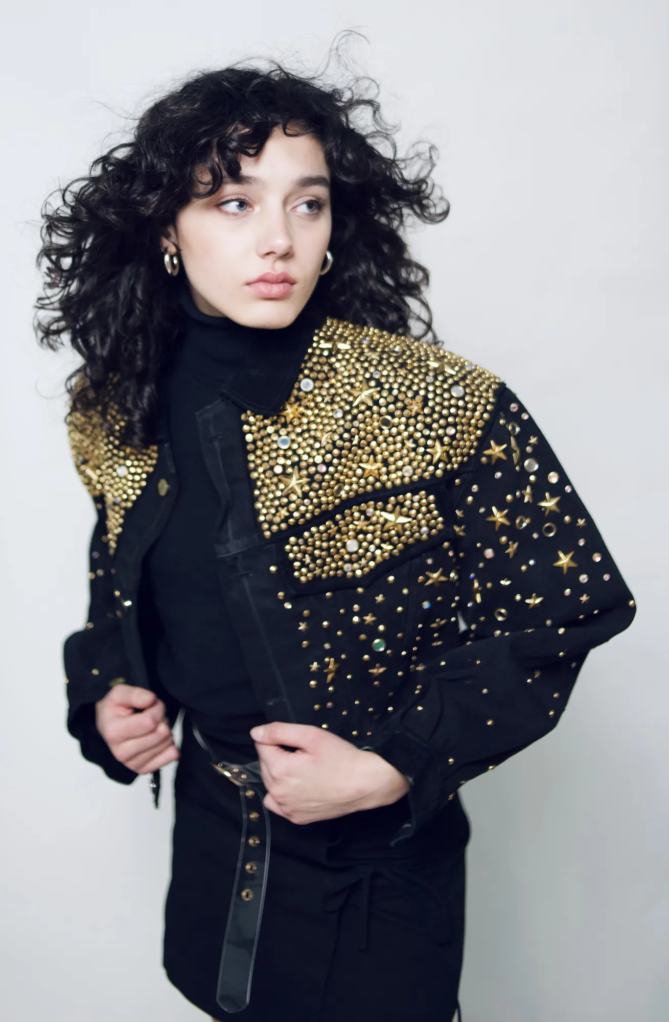 Woman with curly hair in a gold-embellished black jacket